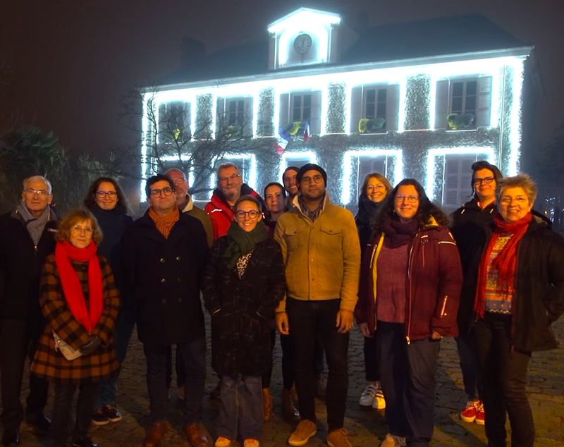 EPB-Video_4 Vignette de la vidéo des vœux 2026 de notre collectif de citoyen·nes. On voit un groupe de personnes avec en arrière plan la mairie illuminée de nuit.